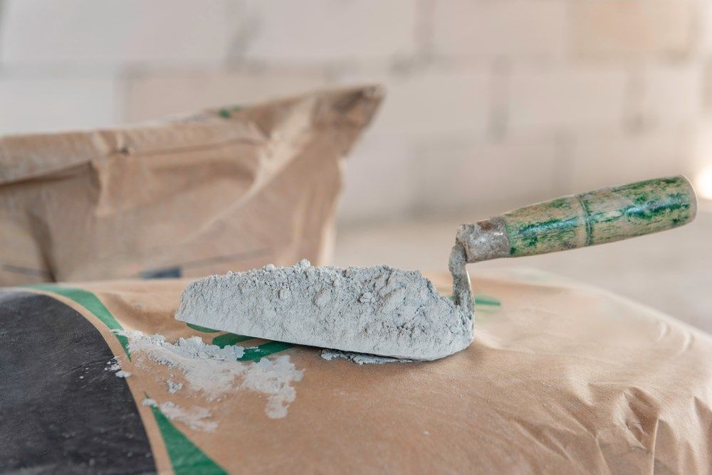 A Trowel with Cement on A Bag of Cement — Cessnock Landscaping Supplies In Maitland, NSW