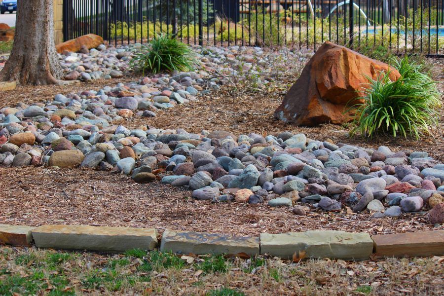 Rock Garden with Riverbed of Stones, Edged by Brick — Cessnock Landscaping Supplies In North Rothbury, NSW