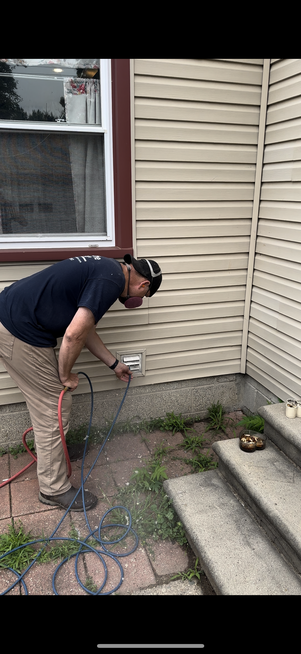 A man is spraying water on the side of a house.