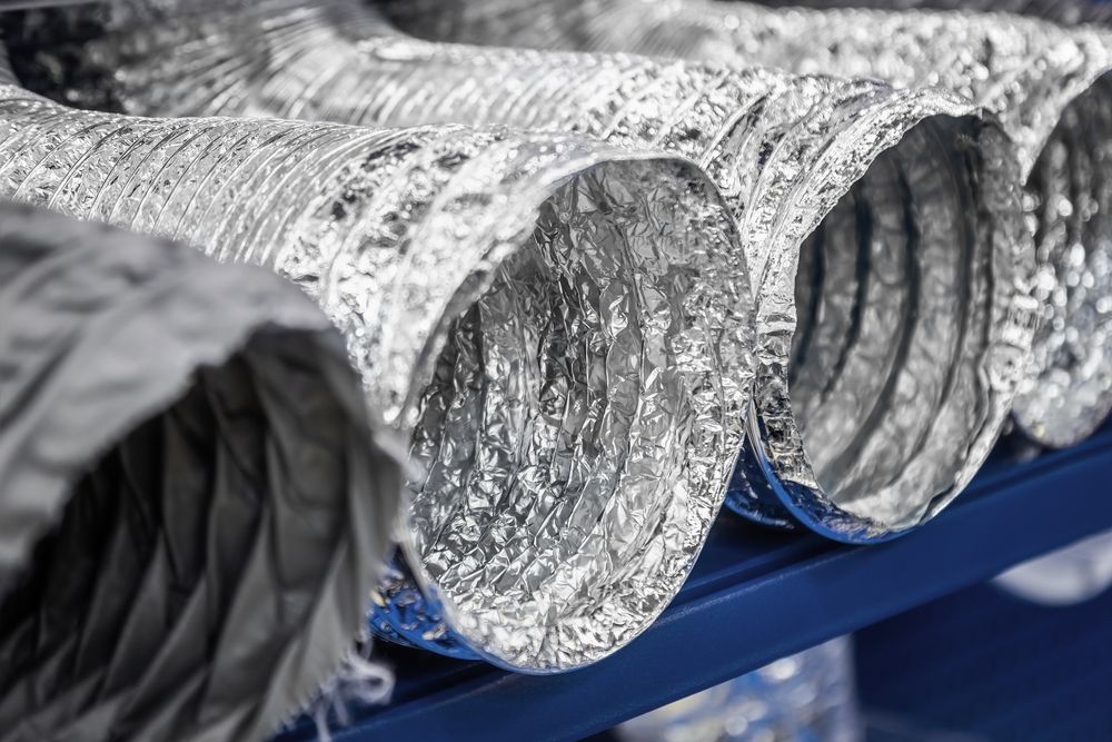 A bunch of aluminum ducts are stacked on top of each other on a shelf.