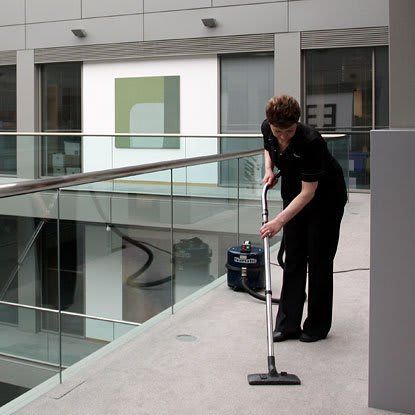 woman hoovering carpet at business site