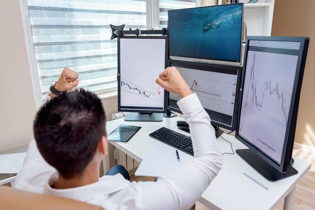 A man is sitting in front of a computer with his arms in the air.