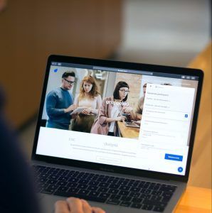 A person is using a laptop computer with a group of people on the screen.