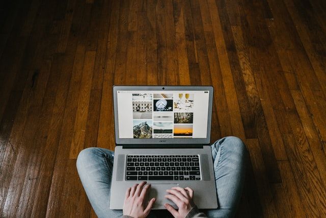 A person is sitting on the floor using a laptop computer.