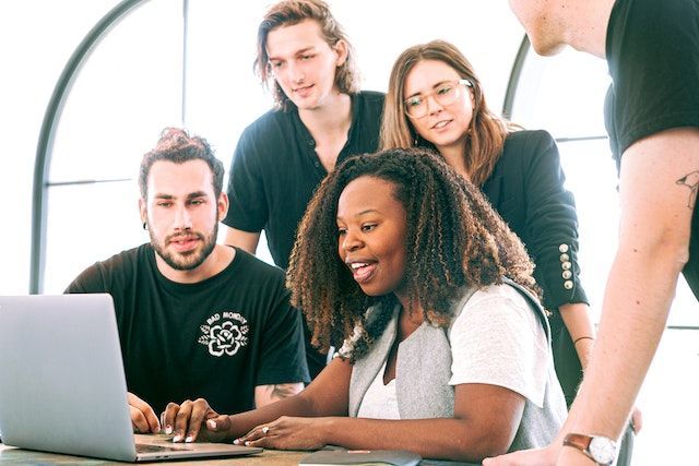 A group of people are looking at a laptop computer.