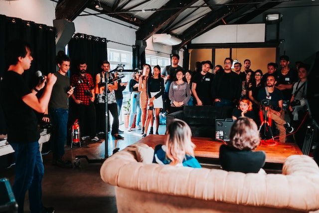 A group of people are standing around a couch in a room.