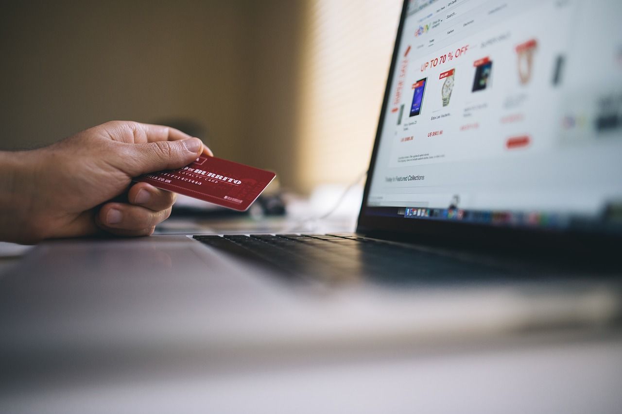 A small shopping cart next to a laptop.