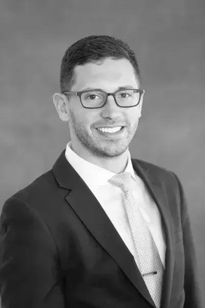 A man in a suit and tie is smiling in a black and white photo.