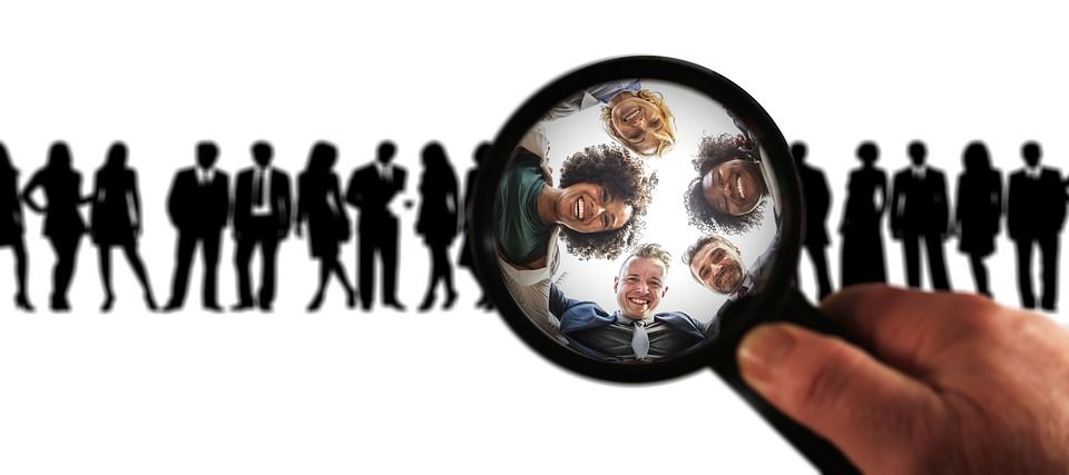 A person is holding a magnifying glass over a group of people.