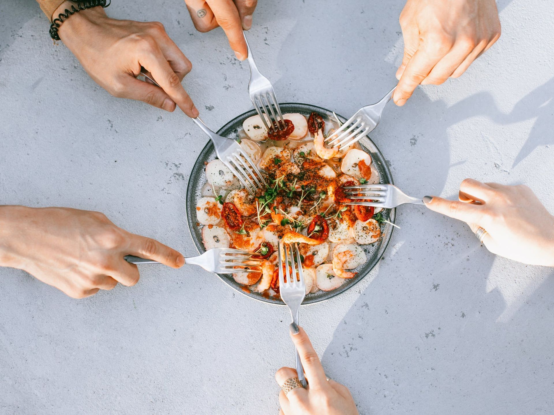 A group of people are eating a plate of food with forks.