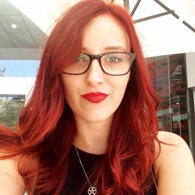 A woman with red hair and glasses is taking a selfie.