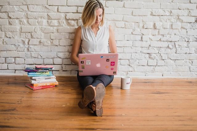 A woman is sitting on the floor using a laptop computer.