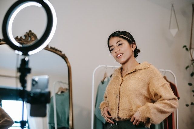 A woman is standing in front of a mirror with a ring light.