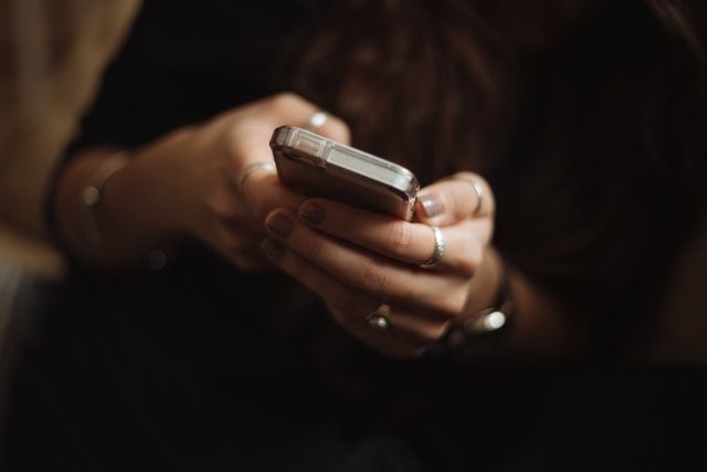 A woman is holding a cell phone in her hands.