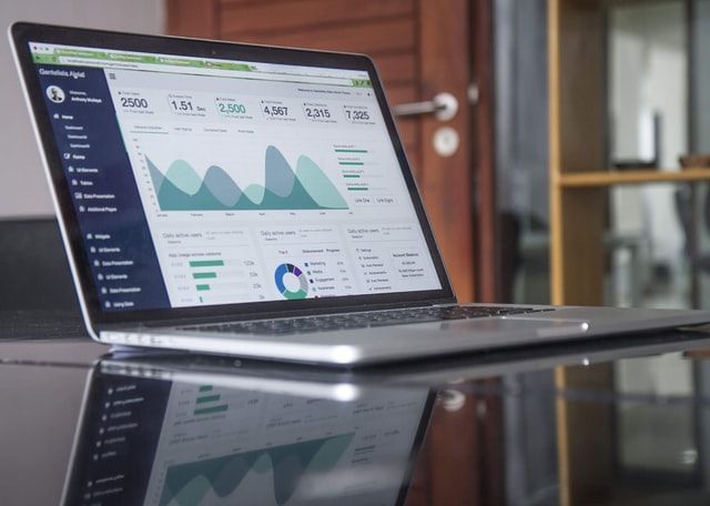 A laptop computer with a graph on the screen is sitting on a table.