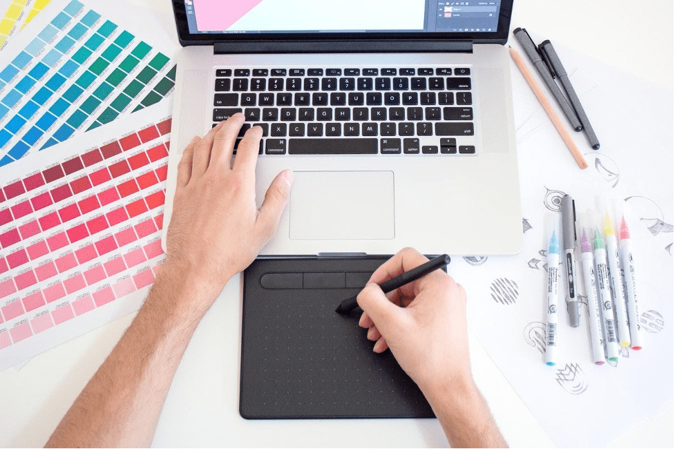 A person is using a laptop computer and a graphic tablet.