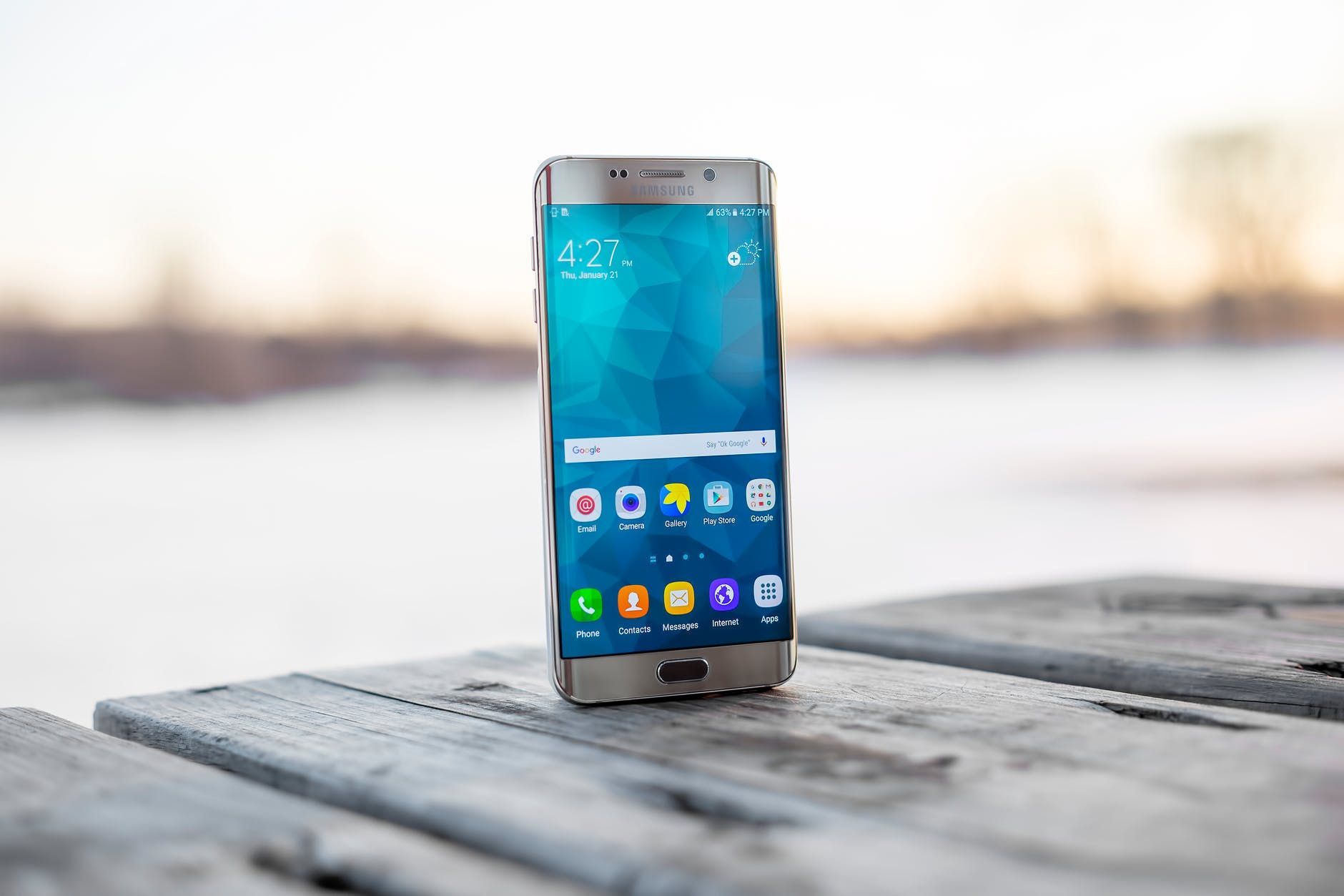 A cell phone is sitting on top of a wooden table.