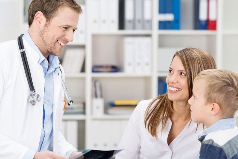 A doctor is talking to a woman and a child.