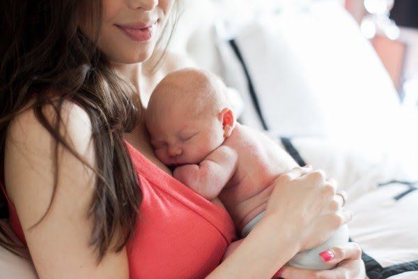 A woman is holding a newborn baby in her arms.