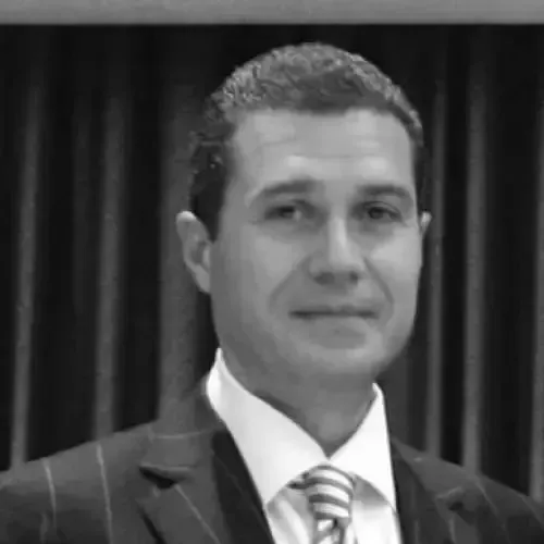 A man in a suit and tie is smiling in a black and white photo.