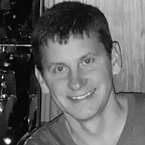 A man is smiling in a black and white photo.