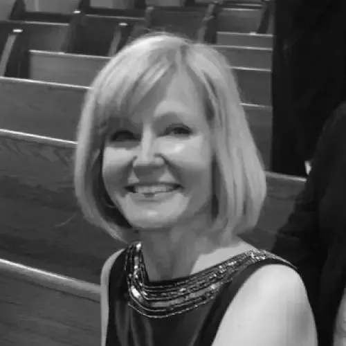 A woman in a black dress is smiling in a black and white photo.