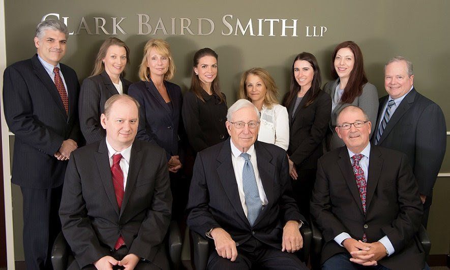 A group of people posing for a picture in front of a wall that says clark baird smith llp