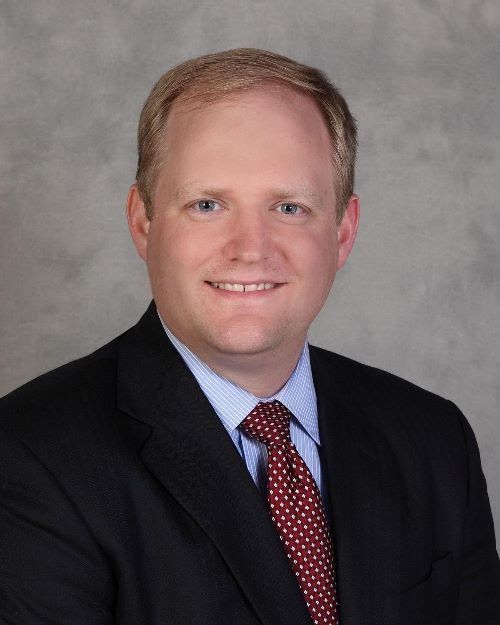 A man in a suit and tie smiles for the camera