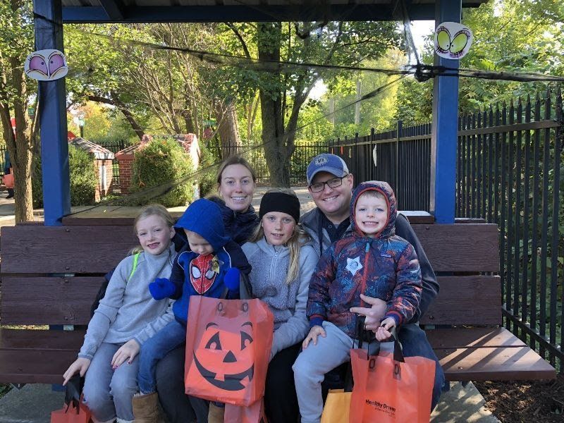 A family is sitting on a bench holding trick or treat bags