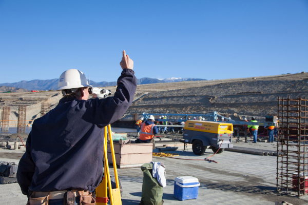 A man in a hard hat is pointing at something in the distance