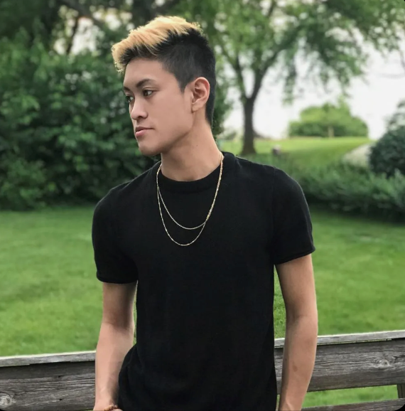A young man wearing a black shirt and a gold chain