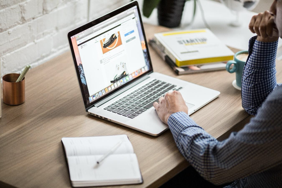 A man is sitting at a desk using a laptop computer.