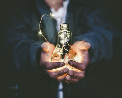 A person is holding a light bulb in their hands.