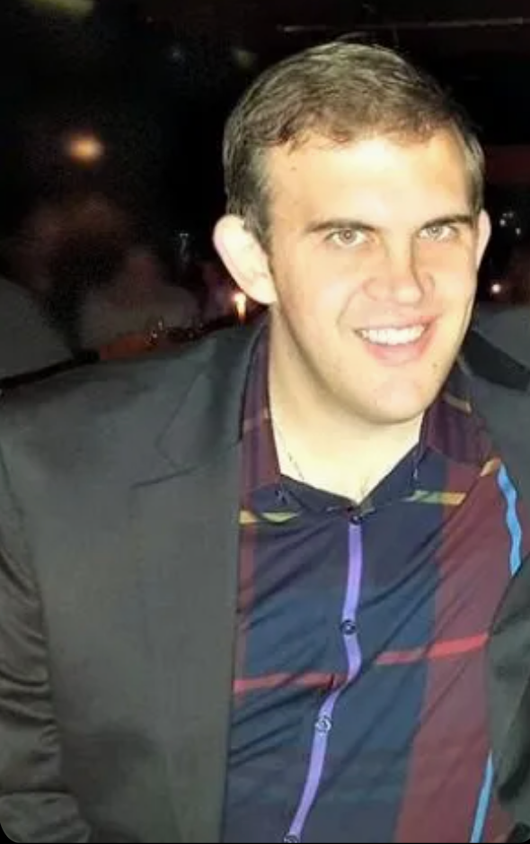 A man in a suit and striped shirt is smiling for the camera.