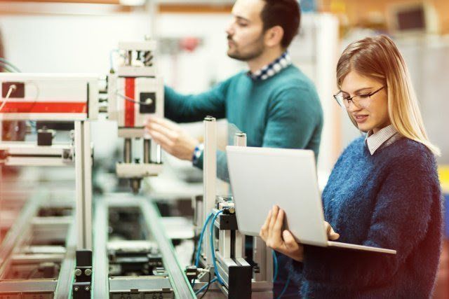 A man and a woman are working on a machine in a factory.