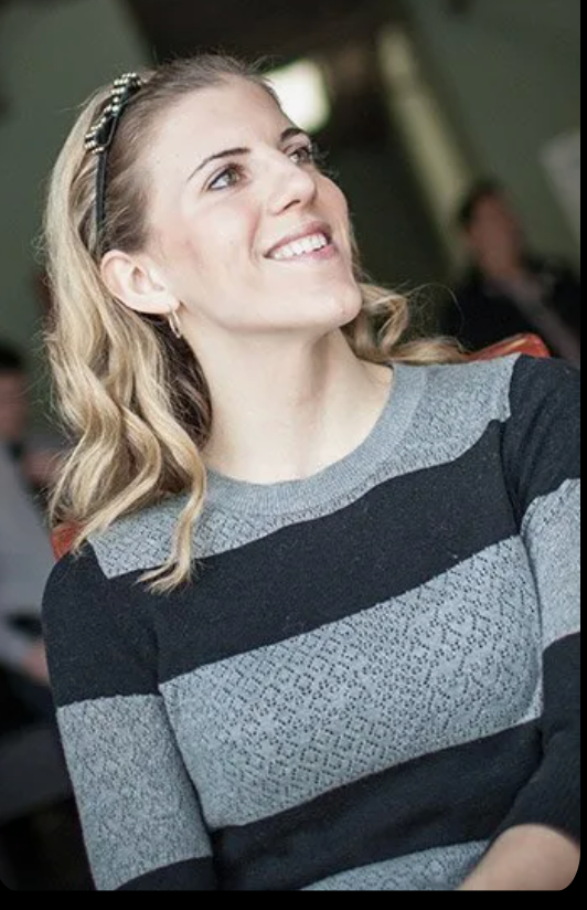 A woman in a striped sweater is smiling and looking up.