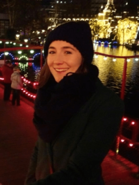 A woman wearing a black hat and scarf smiles for the camera