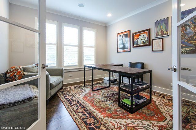 A home office with a desk , chairs , and a rug.