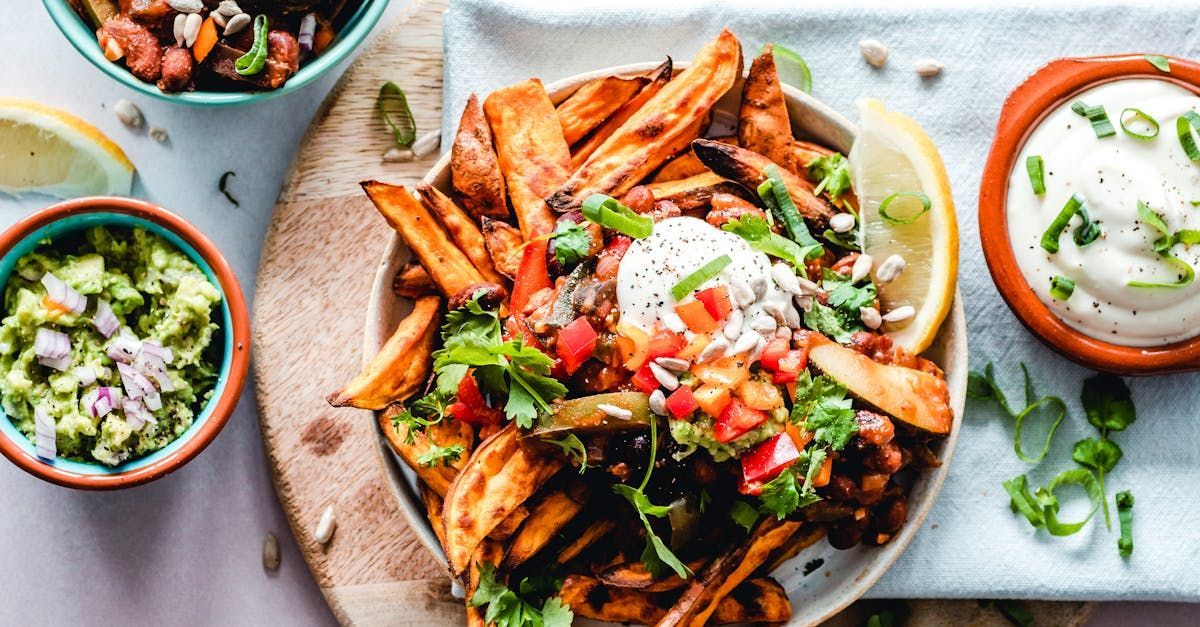 A plate of french fries with guacamole and sour cream on a table.