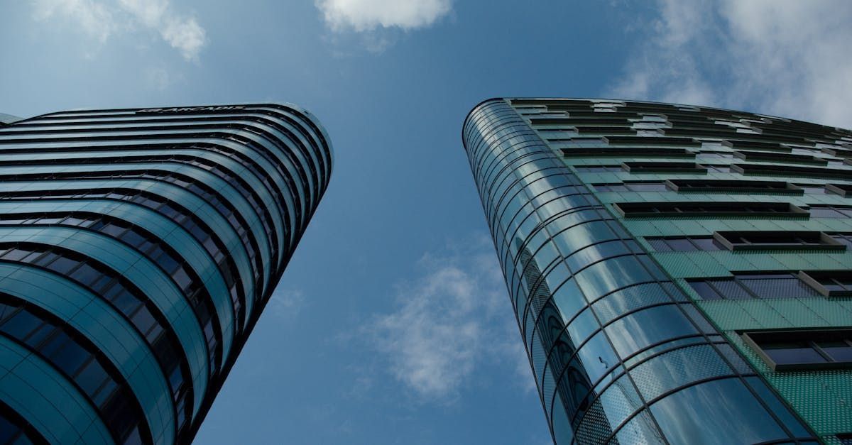 Two tall buildings are against a blue sky with clouds.