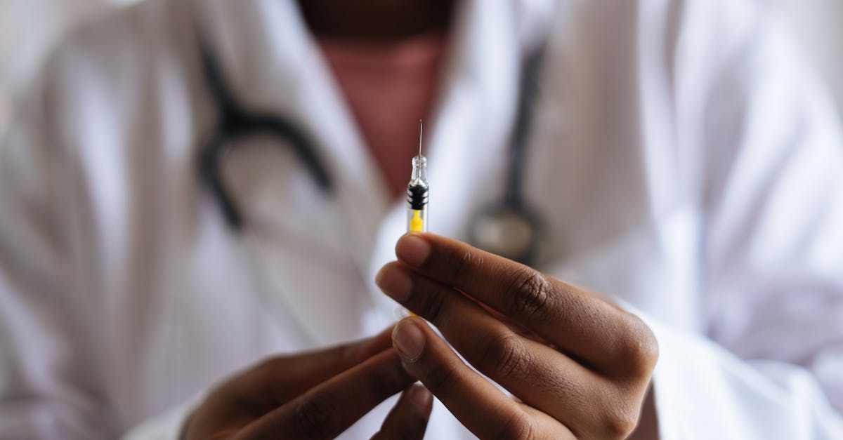 A doctor is holding a syringe in his hands.