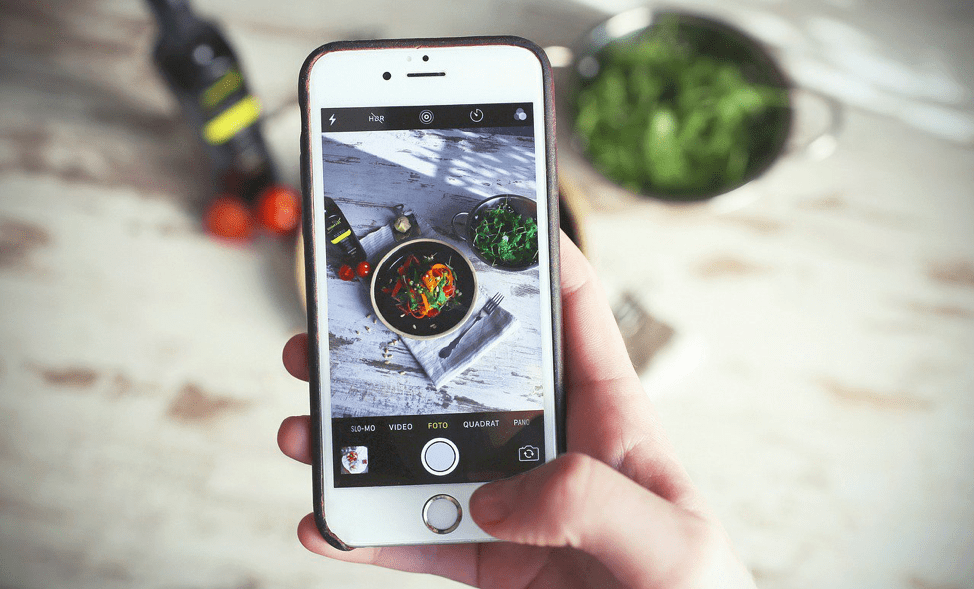 A person is taking a picture of a bowl of food on a cell phone.