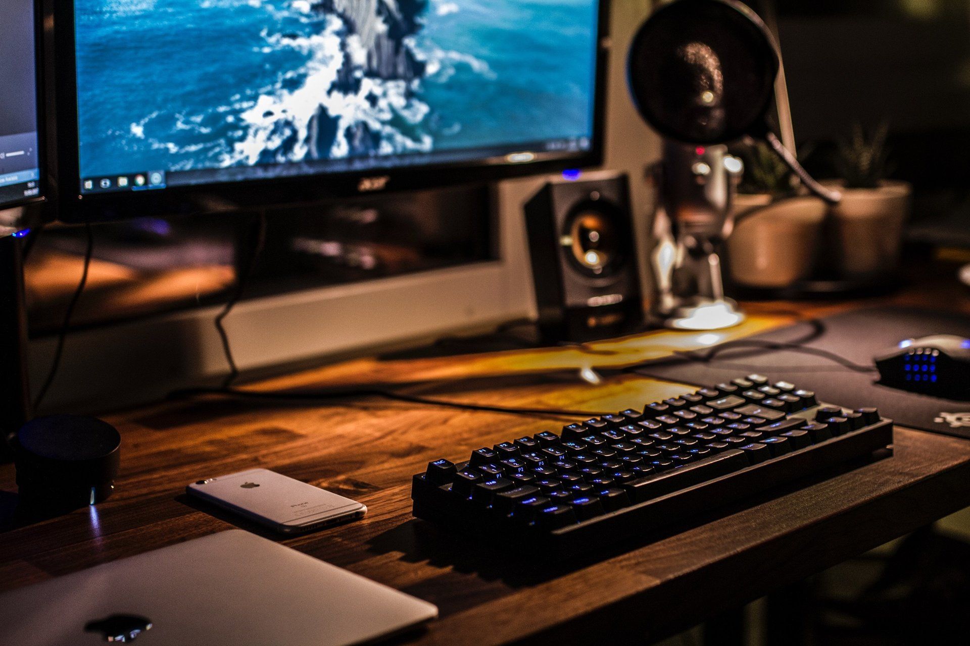 A keyboard is sitting on a wooden desk next to a computer monitor.