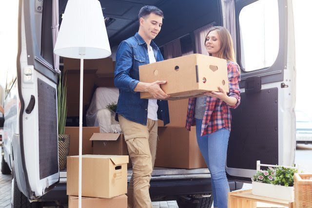 A man and a woman are loading boxes into a van.