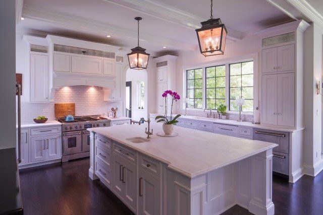 A kitchen with white cabinets and a large island in the middle.