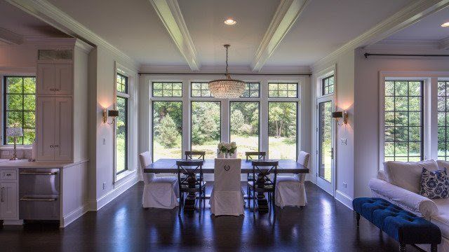 A dining room with a table and chairs and lots of windows.