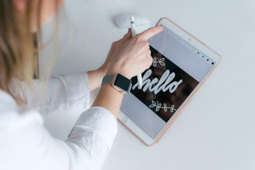 A woman is writing on a tablet with a pen.