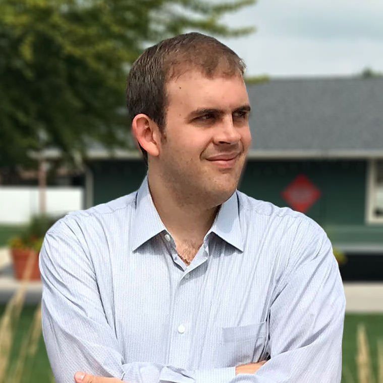 A man in a suit and striped shirt is smiling for the camera.