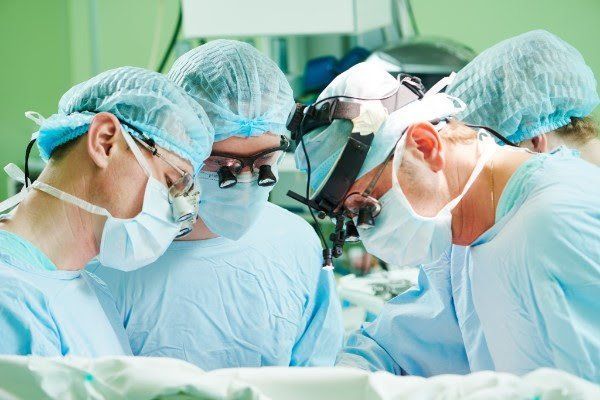 A group of surgeons are operating on a patient in an operating room.