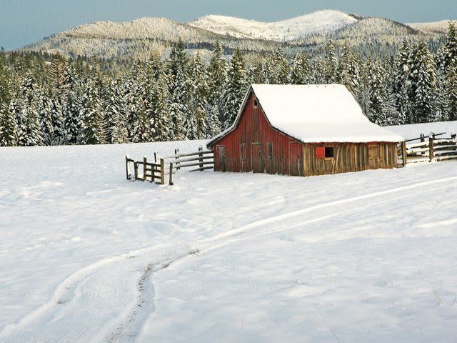 A red barn in the middle of a snowy field